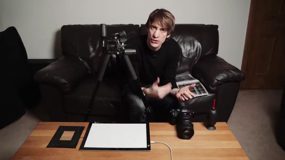 Camera, macro lens, light pad, and tripod laid out on table
