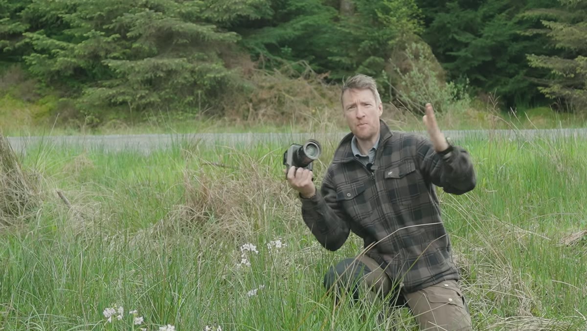 Heaton holding camera close to wildflowers at minimum focus distance